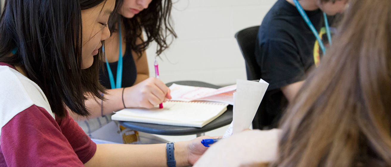Student in classroom focusing on writing
