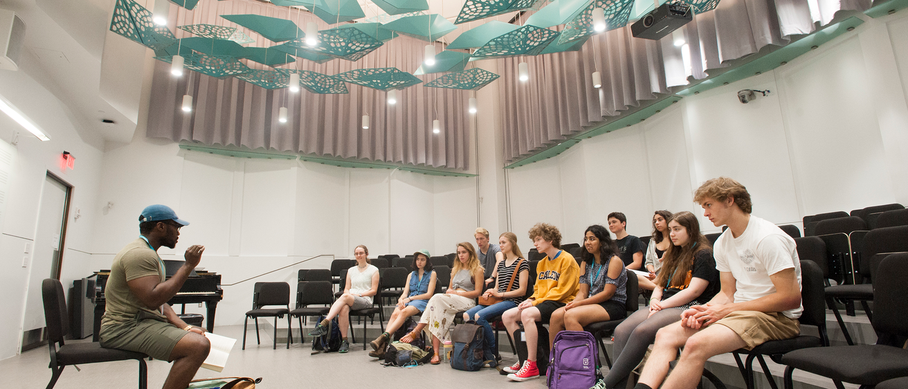 Students in group, seated, gathered around instructer