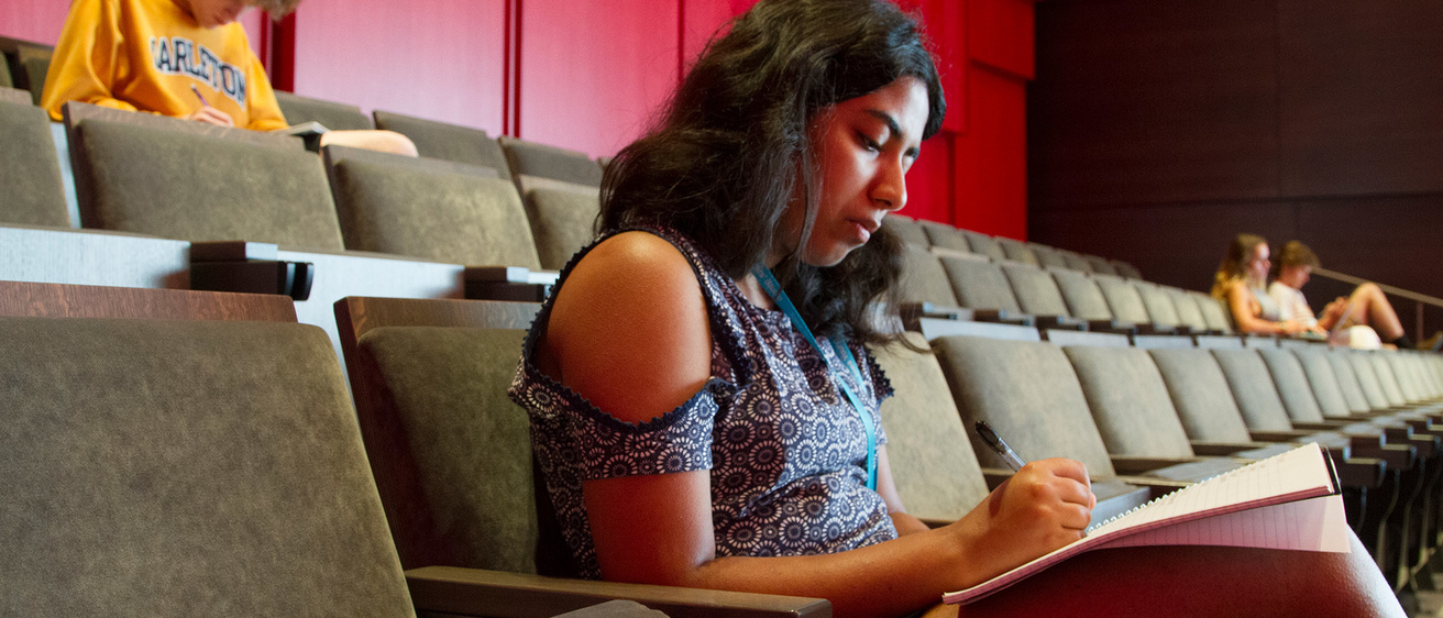 Student writing in auditorium