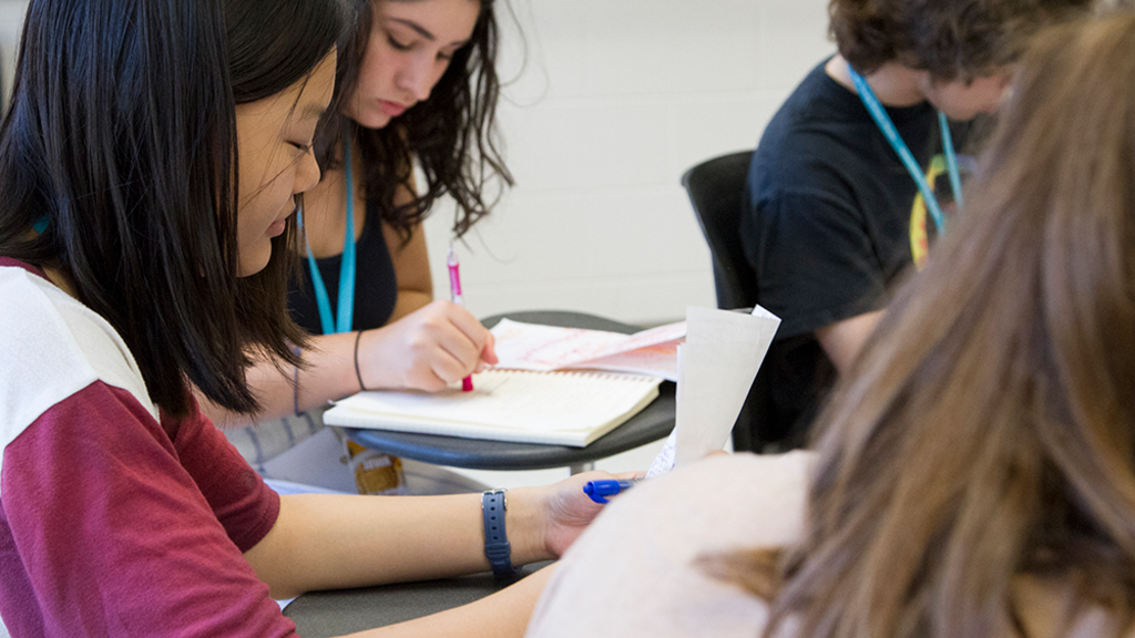 Student in classroom focusing on writing